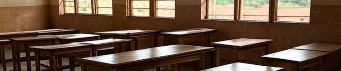 Empty classroom with wooden desks and chairs, highlighting education challenges during the new school term.