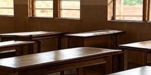 Empty classroom with wooden desks and chairs, highlighting education challenges during the new school term.