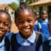 Group of smiling school children in uniform outdoors, representing education and community support by Pearl Global Ministries.